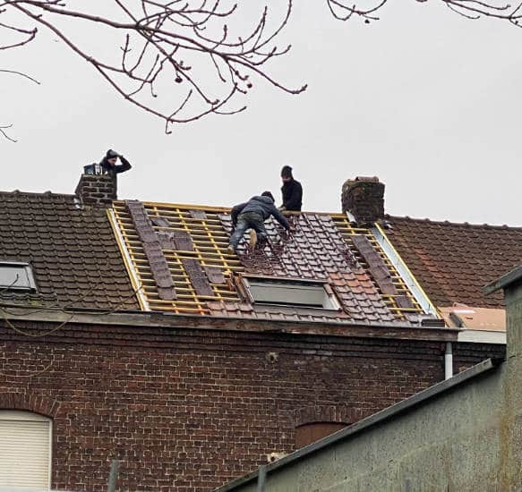 Vue sur un chantier de rénovation de toiture assuré par solution toiture sur une maison traditionnelle, en brique rouge, dans le nord toiture en tuiles plate